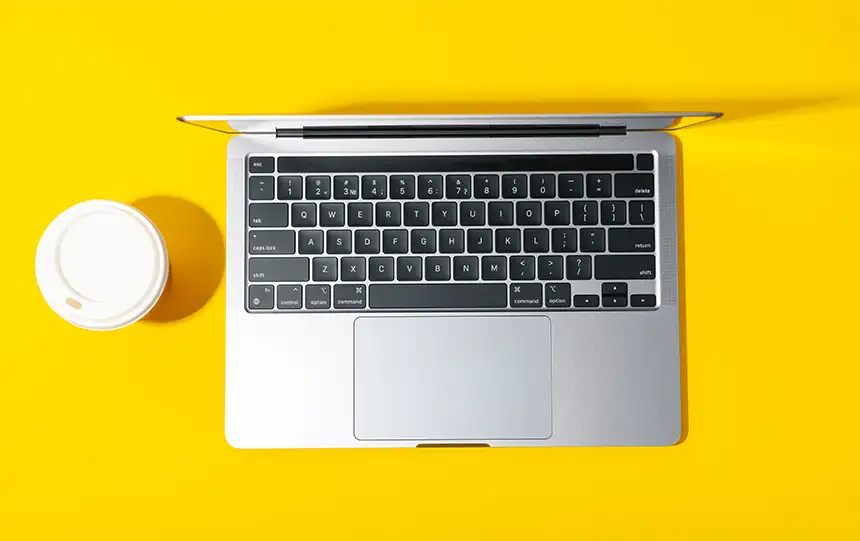 Computador com copo ao lado.